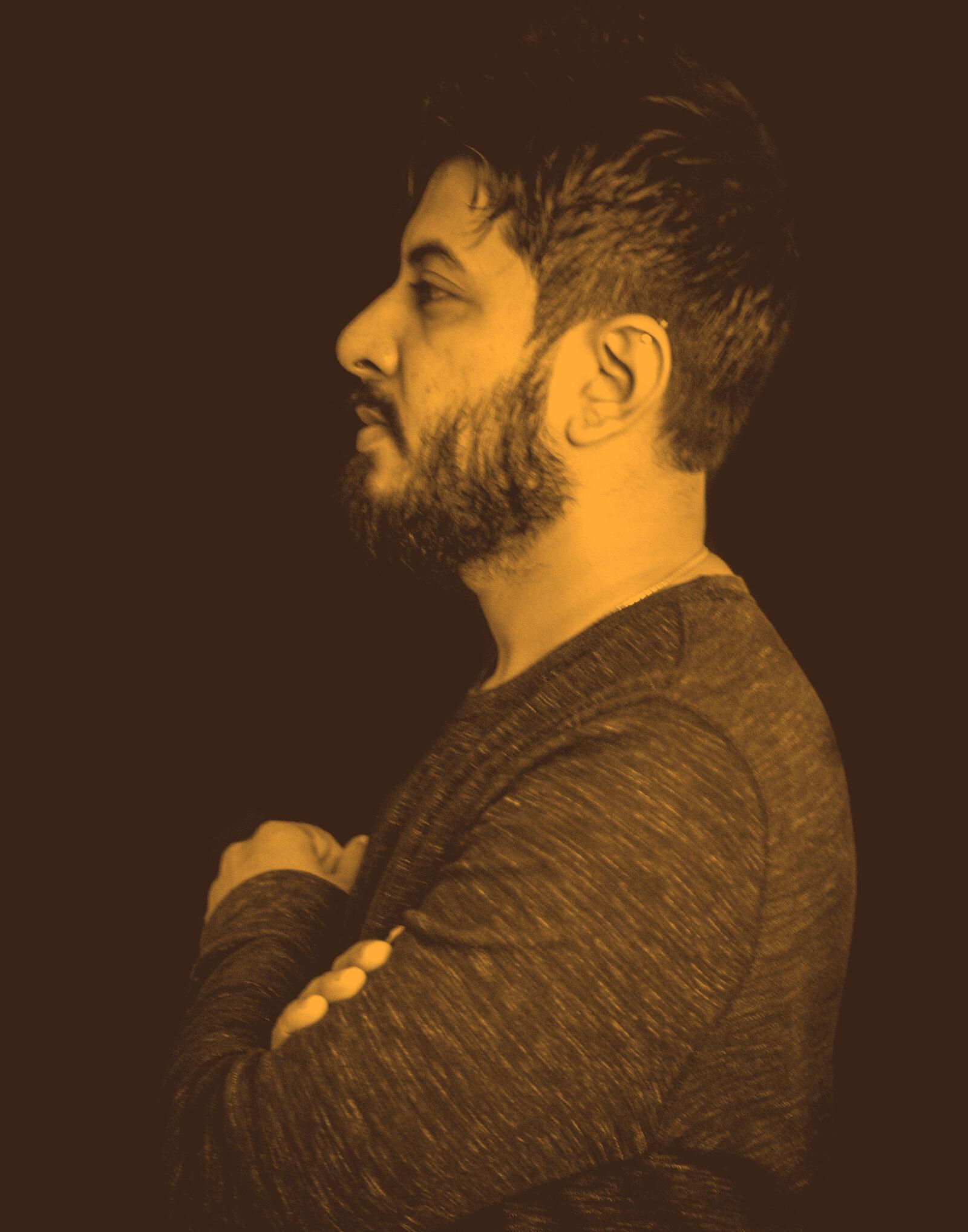 Abhi Maisekar in profile, black and white, against a black background.